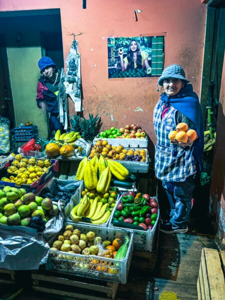 Colorful fruit market in Machachi, Ecuador, featuring vibrant displays of bananas, apples, and citrus, with locals engaged in trade.