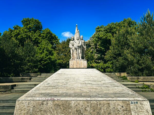 Buzesti Brothers monuments stand prominently amidst lush greenery in Craiova, Romania, under a clear blue sky.