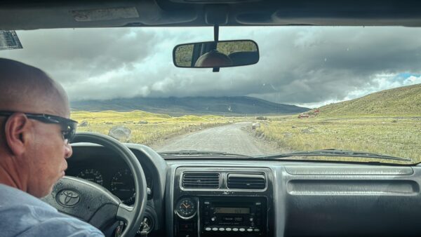 Driving through Cotopaxi National Park, Ecuador, with rolling hills and dramatic clouds visible in the distance.