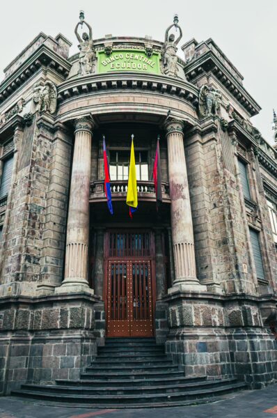 Banco Central features ornate architecture with intricate stonework and colorful flags in Quito, Ecuador.