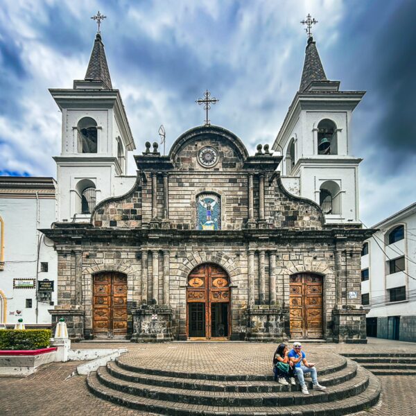 Stunning Ibarra Cathedral showcases intricate stonework and twin spires, surrounded by a charming plaza and overcast sky.