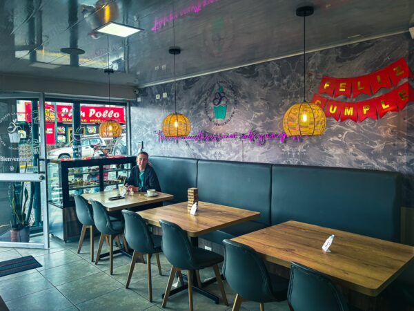 Mousse candy shop interior in Machachi, Ecuador features wooden tables, stylish black chairs, and festive decorations.