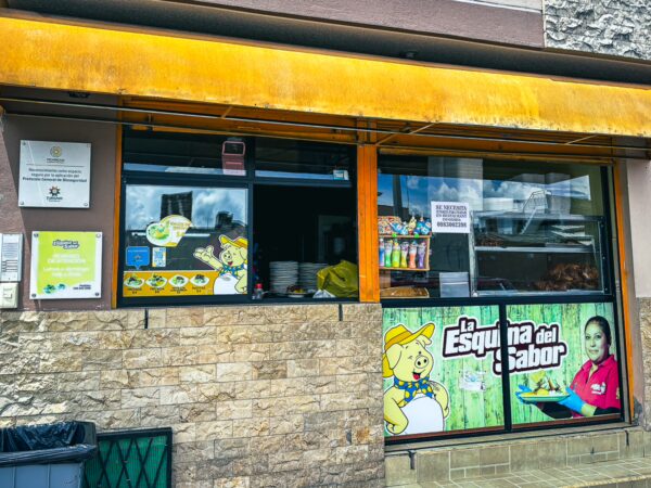 La Esquina del Sabor features a vibrant yellow awning and colorful signage, showcasing local flavors in Machachi, Ecuador.