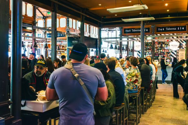 Crowd enjoying tapas at Mercado de San Miguel, vibrant stalls offering Spanish delicacies in Madrid, Spain.
