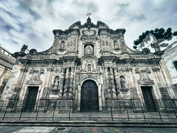 Intricate baroque façade of the Church of the Society of Jesus, featuring ornate details and a dramatic sky in Quito, Ecuador.