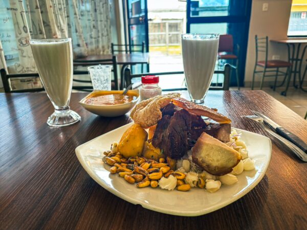 Delicious traditional Ecuadorian meal at La Esquina del Sabor in Machachi, featuring grilled meats, corn, and refreshing drinks.