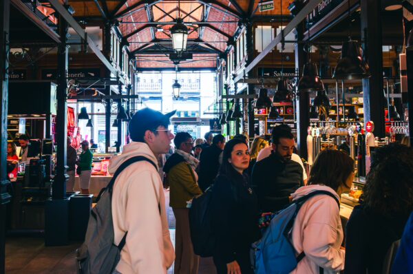 Crowded Mercado de San Miguel features vibrant stalls and visitors enjoying local delicacies in Madrid, Spain.