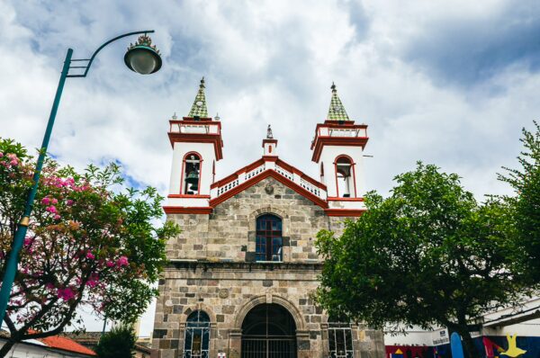 San Agustín Church stands prominently in Ibarra, Ecuador, featuring striking red accents and twin spires against a cloudy sky.