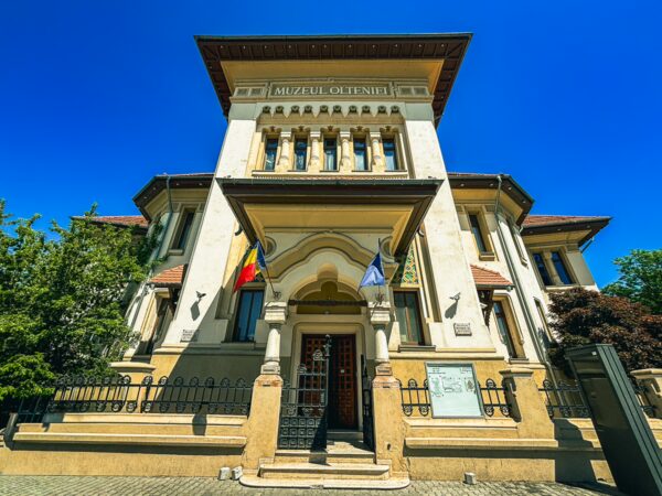 Oltenia Museum showcases impressive architecture in Craiova, Romania, featuring vibrant colors against a clear blue sky.