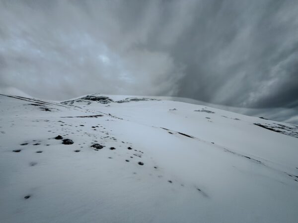 Snow-covered slopes and dramatic gray skies at Mount Cotopaxi, Ecuador, showcasing the serene beauty of the high-altitude landscape.