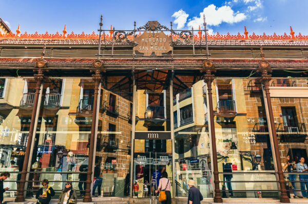 Bustling Mercado de San Miguel in Madrid showcases a vibrant entrance with ornate architecture and lively visitors.