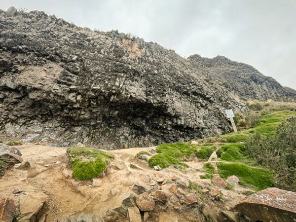Pichincha Volcano’s rugged terrain features dark rocky outcrops and lush green moss along the hiking path in Ecuador.
