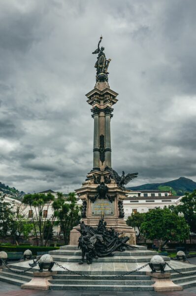 Independence Monument in Quito, Ecuador, features a prominent statue atop a column surrounded by a decorative fountain and green landscaping.