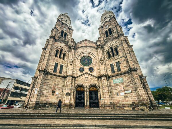 Basilica La Dolorosa in Ibarra, Ecuador showcases intricate stone architecture and looming twin towers under a moody sky.
