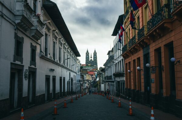 Charming street in Quito, Ecuador, lined with colonial buildings and flags, leading to twin towers in the distance.