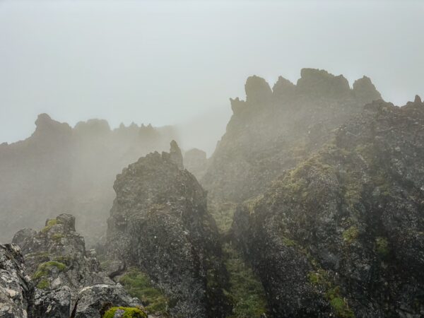 Misty Imbabura Volcano features rugged rock formations cloaked in fog, with greenery peeking through the rocky landscape in Ecuador.