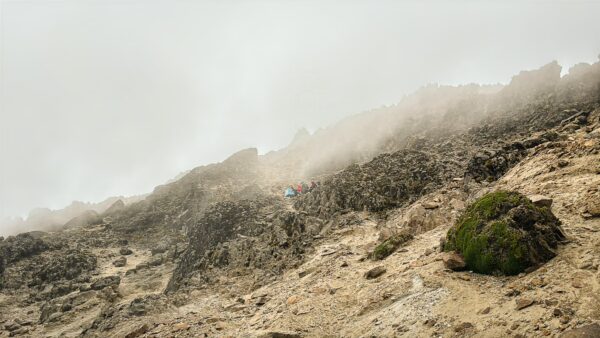 Foggy terrain with rocky slopes and patches of green vegetation on Pichincha Volcano in Ecuador, showcasing its rugged beauty.
