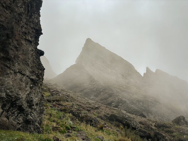 Rugged volcanic peaks rise through misty clouds at Ruminahui, Ecuador, highlighting dramatic rock formations and lush green terrain.