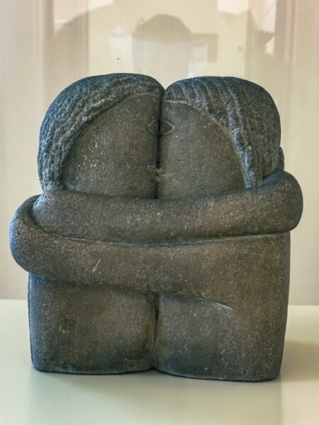Elegant stone sculpture of two figures embracing, showcased inside the art museum in Craiova, Romania.