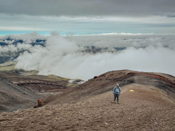 Stunning views of Mount Cotopaxi's rugged landscape, with a lone hiker silhouetted against cloudy skies in Ecuador.