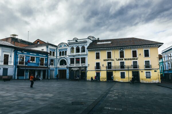 Historic buildings in Plaza del Teatro, Quito, Ecuador, showcase colonial architecture with vibrant colors and a cloudy sky.
