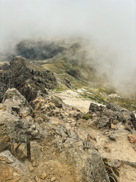 Rugged terrain and rocky cliffs are shrouded in mist at Rucu Pichincha Volcano, Ecuador, highlighting its dramatic landscape.