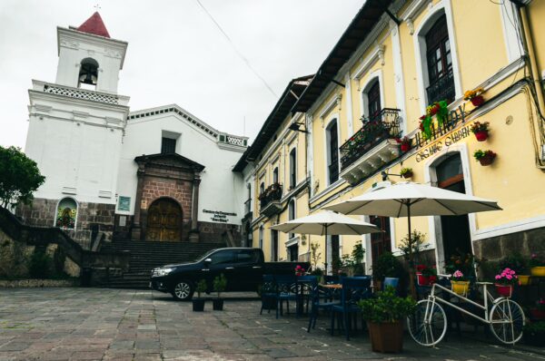 Plaza San Blas features colorful buildings, a charming café with umbrellas, and the historic church in Quito, Ecuador.