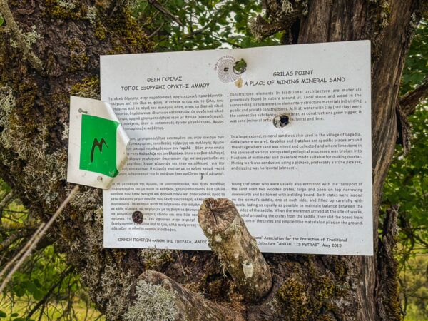 Informative signage attached to a tree in Valtesiniko, Arcadia, Greece, detailing local history and natural features.