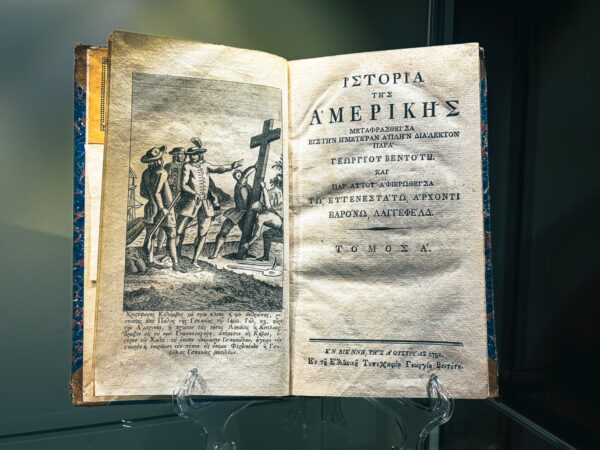 Historical book displayed at the art museum features Greek text and an illustration of explorers, found in Craiova, Romania.