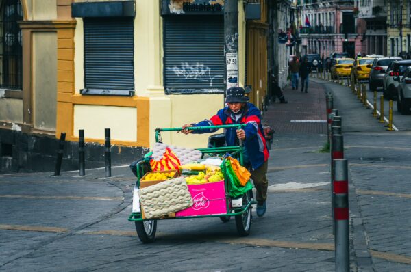 Brightly colored fruit cart being pushed by a vendor on a bustling street in Guayaquil, Quito, Ecuador.