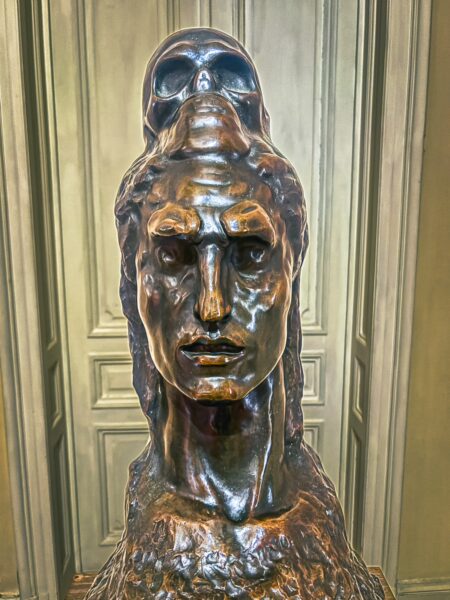 Bronze sculpture featuring a figure with a skull atop its head, showcasing detailed craftsmanship at the Art Museum in Craiova, Romania.