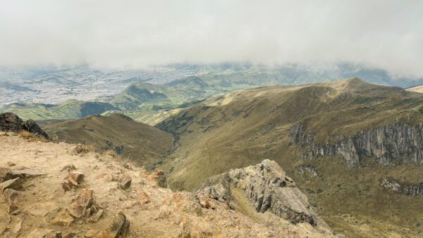 Rucu Pichincha volcano reveals expansive green valleys and rugged terrain set against a cloudy sky in Ecuador.