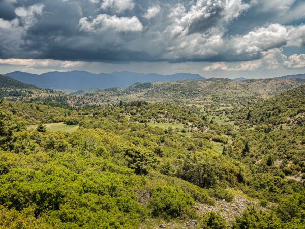 Lush green hills and valleys under a dramatic sky near Lagadia, Arcadia, Greece, showcasing the region's natural beauty.
