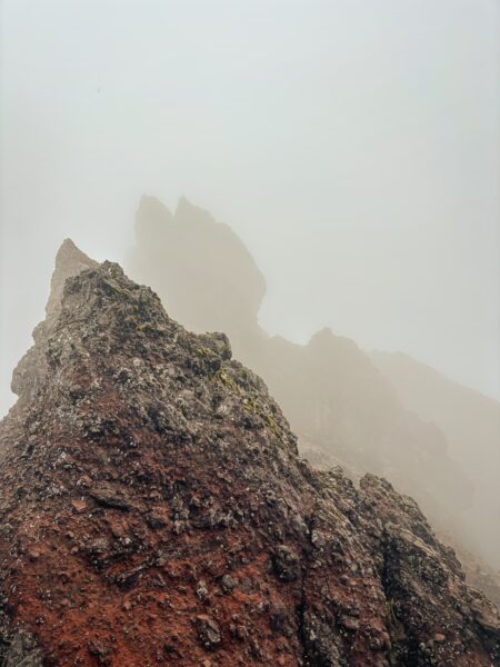 Misty volcanic landscape featuring rugged, reddish rock formations near Raminahui, Ecuador, creating an atmospheric scene.