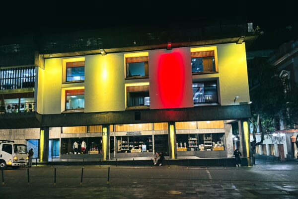 Colorful illuminated building at night along Sucre Street in Quito, Ecuador, showcasing a vibrant urban atmosphere.
