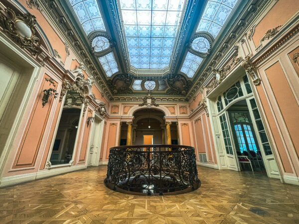 Ornate interior of the art museum in Craiova, Romania, featuring a stunning glass ceiling and intricate moldings.