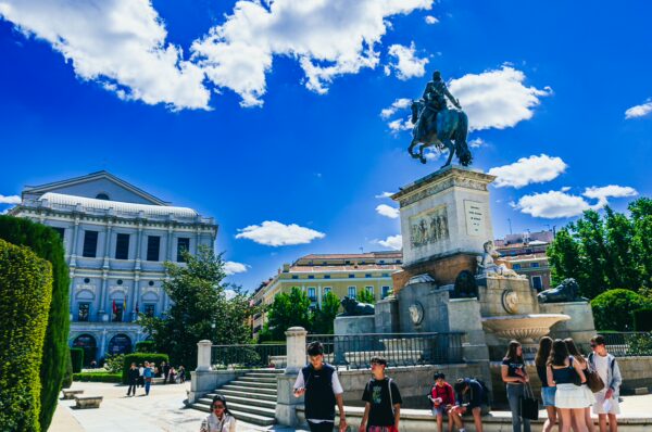 Equestrian monument of Felipe IV stands majestically in Plaza de Oriente, surrounded by lush greenery and bright blue skies in Madrid.