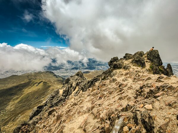 Rugged terrain and rocky summit of Rucu Pichincha Volcano with sweeping views of clouds and the city below in Ecuador.
