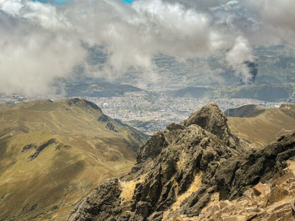 Rucu Pichincha Volcano showcases rugged peaks and a sweeping view of Quito below, with dramatic cloud cover and mountainous terrain.