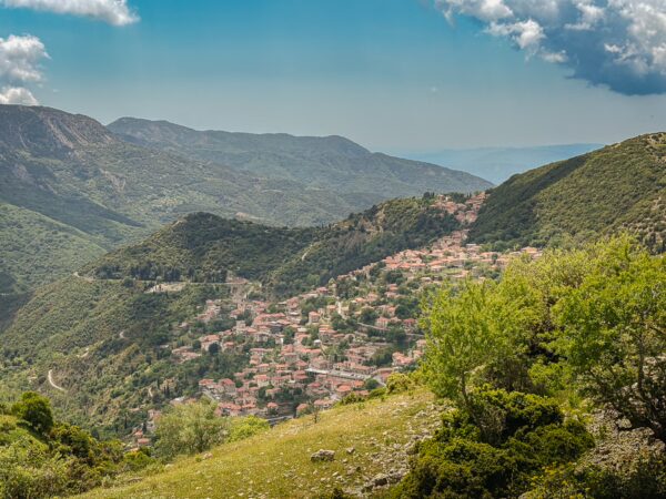 Charming hillside village of Lagadia surrounded by lush green mountains and a clear blue sky in Arcadia, Greece.