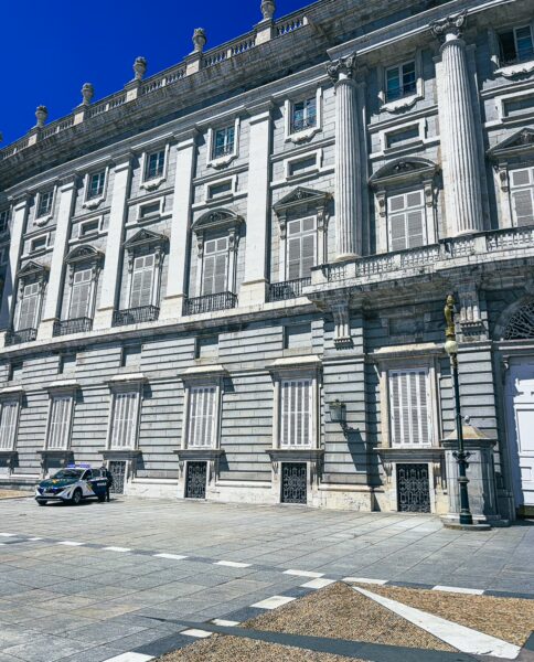 Elegant architecture of Palacio Real in Madrid, showcasing intricate columns and expansive façade under a clear blue sky.