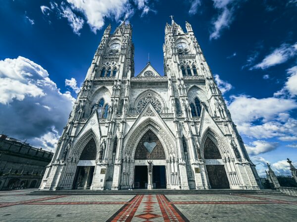 Basilica del Voto Nacional features striking neo-Gothic architecture against a dramatic sky in Quito, Ecuador.