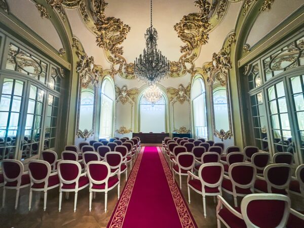 Elegant interior of the art museum in Craiova, Romania, featuring a chandelier and ornate decor with red seating and a patterned carpet.