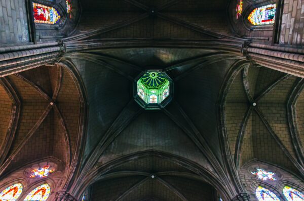 Stunning stained glass windows illuminate the vaulted ceiling of Basilica del Voto Nacional in Quito, Ecuador.