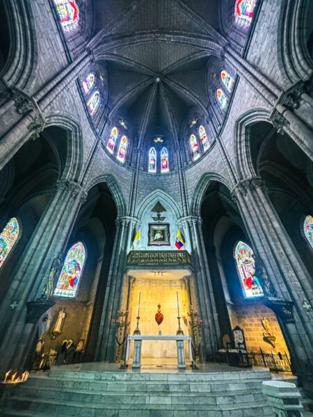 Stained glass windows cast colorful light inside the Basilica del Voto Nacional, highlighting its stunning architecture in Quito, Ecuador.