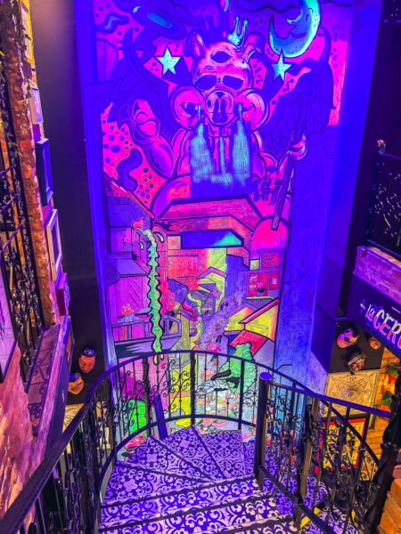 Vibrant mural decorates the stairwell of 69 Andes Brew Pub, showcasing bold colors and street art in Quito, Ecuador.