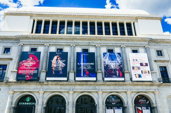 Teatro Real features vibrant promotional banners, showcasing performances against a backdrop of stunning architecture in Madrid, Spain.