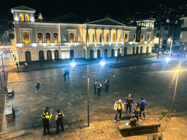 Illuminated Plaza del Teatro in Quito, Ecuador, features a historic building with a lively gathering of people at night.