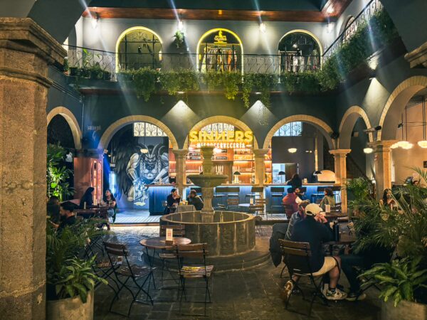 Sinners Microcerveceria in Quito, Ecuador features a vibrant interior with a fountain, lush plants, and cozy seating arrangements.