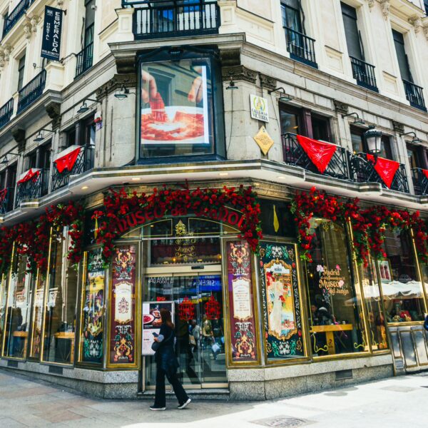 Vibrant storefront adorned with red flowers and festive banners, capturing the lively atmosphere of Madrid, Spain.